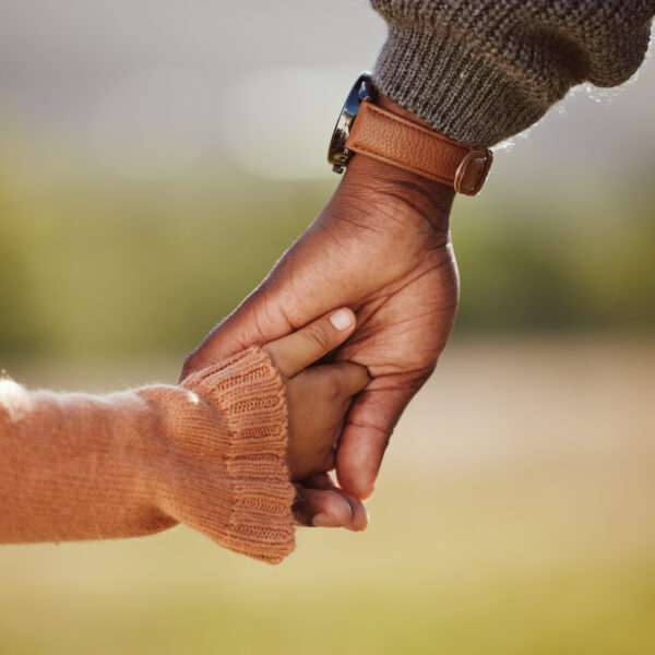 Family, holding hands and girl with father closeup in a park, hands and walking in nature, bond and relax outdoors. Love, trust and parent hands with child in support of trust, peace and unity